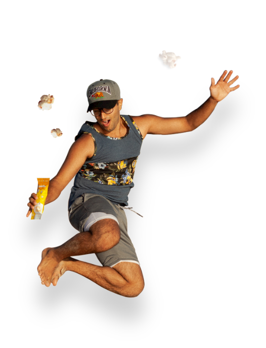 A young man jumping in the air with enthusiasm holding a grab and go pack of poplettes popped sorghum